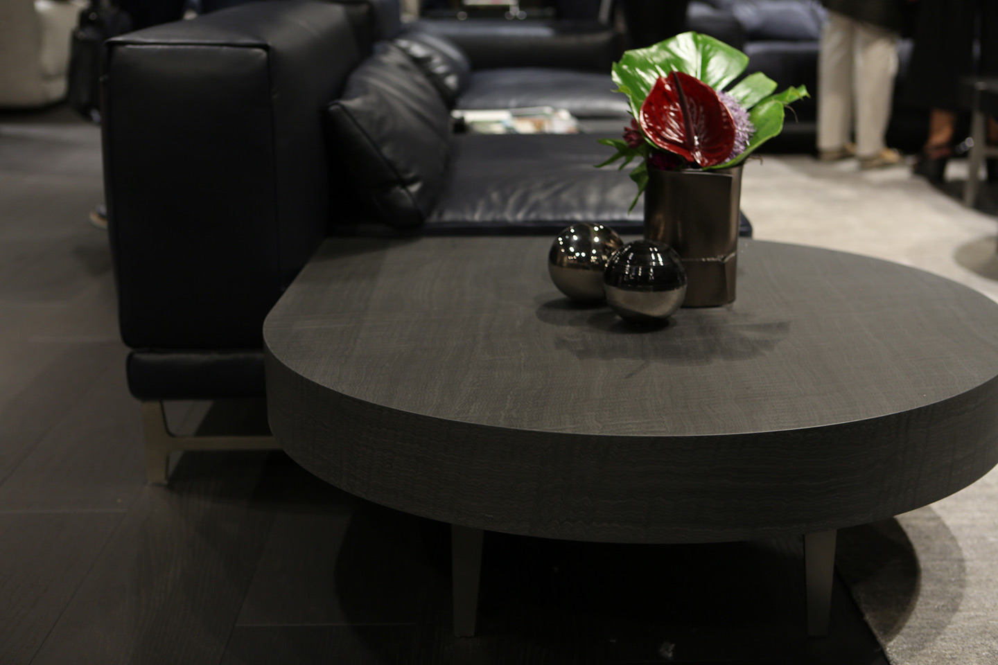 Tavolo grigio di design Natuzzi, con sopra delle sfere cromate e un vaso con foglie e fiori
