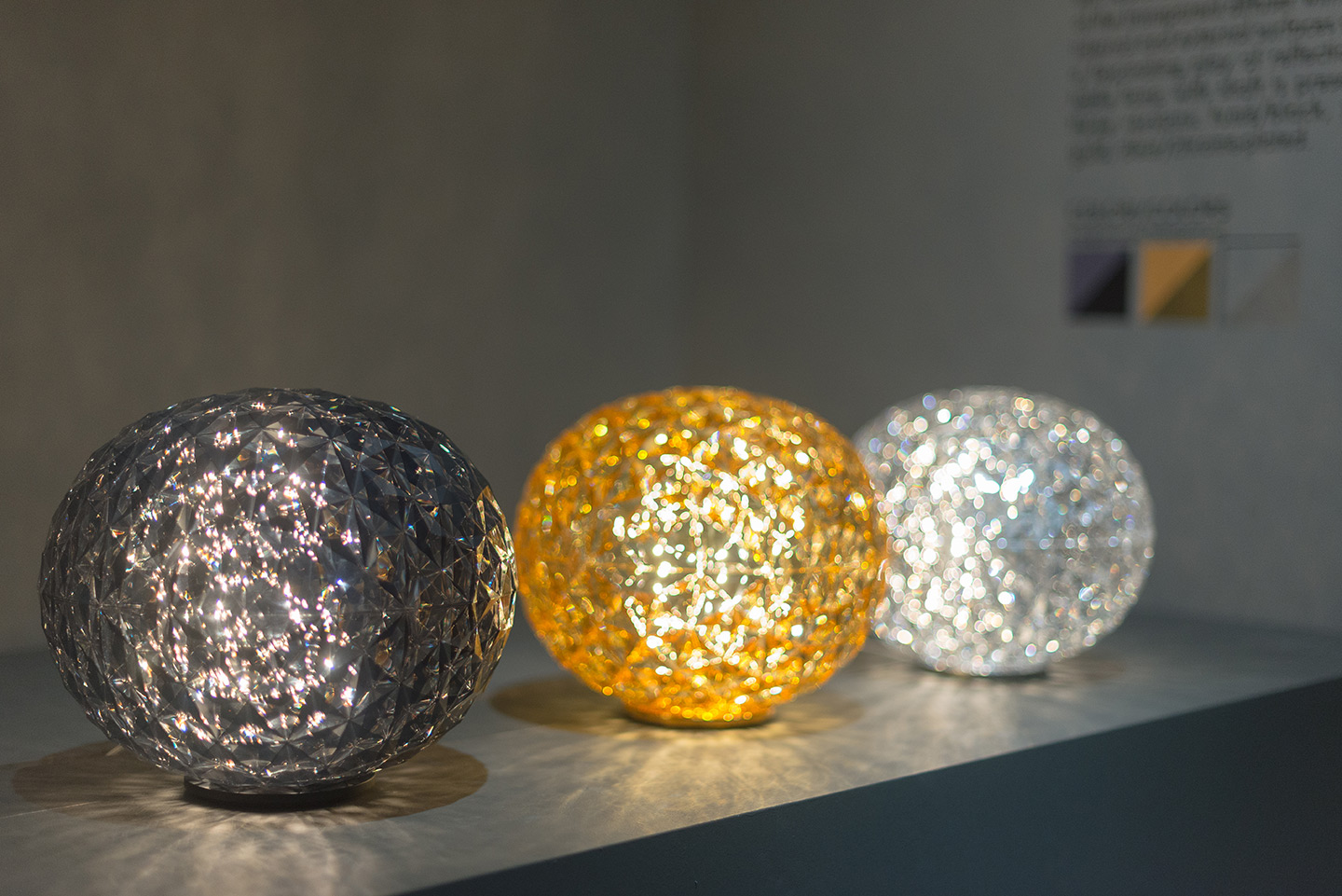 tre lampade di design kartell, disposte in fila: la prima è nera, la seconda è oro e la terza è argento. 